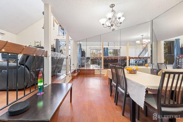 dining area featuring a textured ceiling, a chandelier, wood finished floors, and lofted ceiling