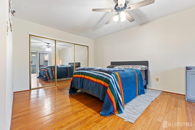 bedroom with wood-type flooring, a closet, a textured ceiling, and ceiling fan