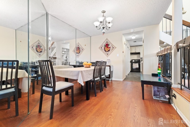 dining space with a textured ceiling, light wood finished floors, a notable chandelier, and stairway