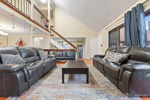 living area with high vaulted ceiling, stairway, a textured ceiling, and wood finished floors
