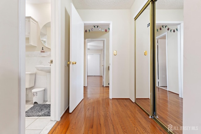 corridor featuring light wood finished floors and a textured ceiling