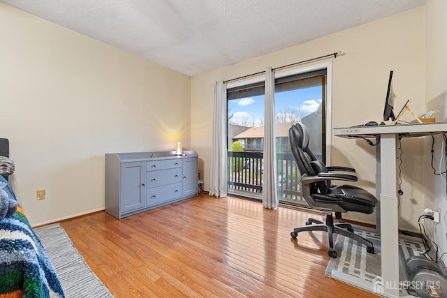 office with light wood-style floors, baseboards, and a textured ceiling