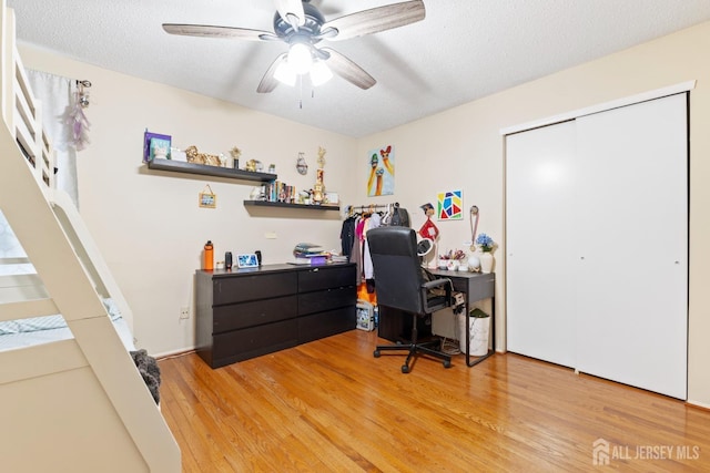 home office featuring light wood-style floors, a textured ceiling, and a ceiling fan