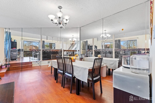 dining space with a notable chandelier, wood finished floors, and a textured ceiling