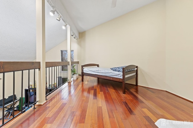 interior space with baseboards, rail lighting, a ceiling fan, high vaulted ceiling, and hardwood / wood-style flooring