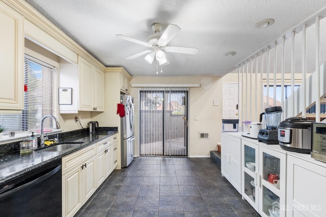 kitchen featuring freestanding refrigerator, cream cabinets, ceiling fan, dishwasher, and a sink