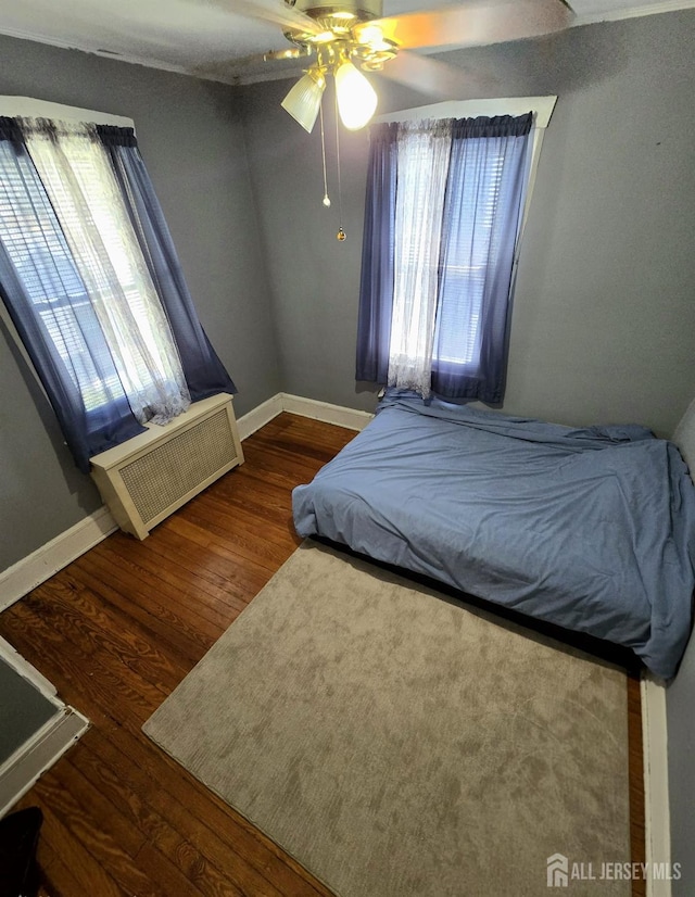 237 Prospect Ave, Dunellen, NJ 08812 - bedroom featuring radiator heating unit, multiple windows, wood finished floors, and a ceiling fan