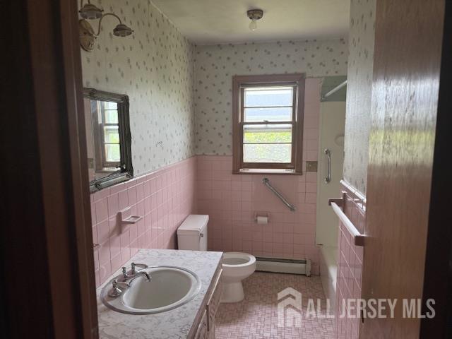 397 Lake Ave, Colonia, NJ 07067 - bathroom with baseboard heating, a shower, wallpapered walls, wainscoting, and tile walls