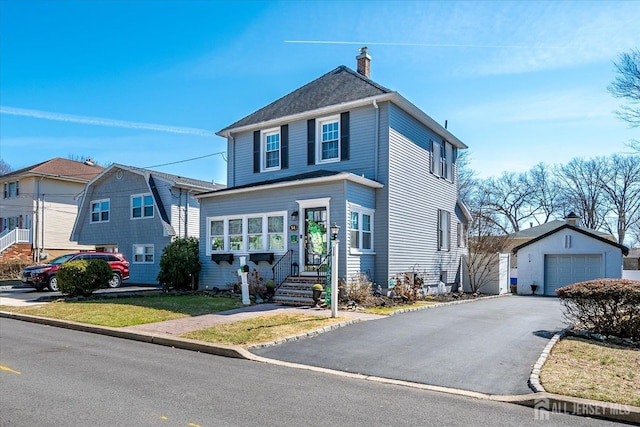 american foursquare style home with aphalt driveway, an outdoor structure, a shingled roof, a garage, and a chimney