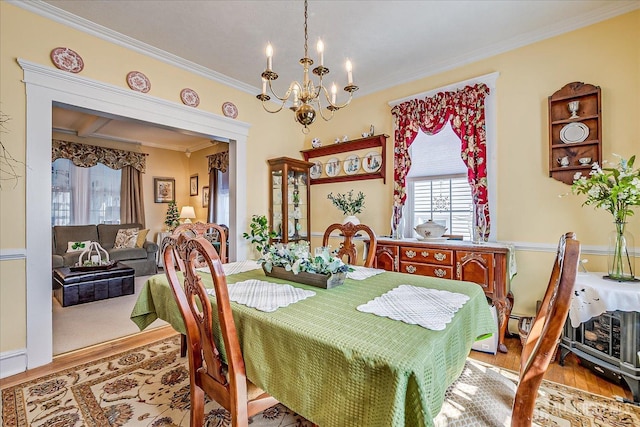 dining area featuring a notable chandelier, ornamental molding, and wood finished floors