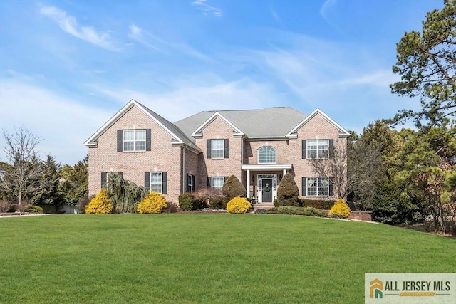 colonial-style house featuring a front lawn and brick siding