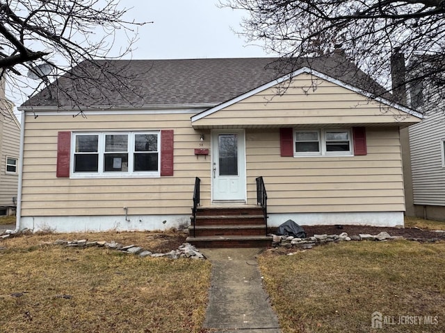 bungalow featuring roof with shingles and a front yard