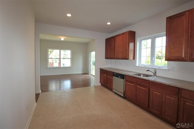 kitchen with stainless steel dishwasher, light stone counters, and sink