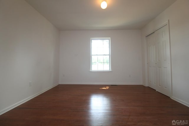 unfurnished bedroom with dark hardwood / wood-style flooring and a closet