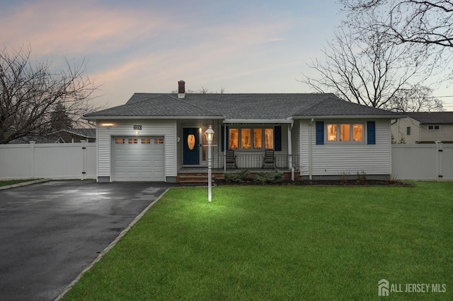 view of front of home featuring a yard, fence, an attached garage, a chimney, and driveway