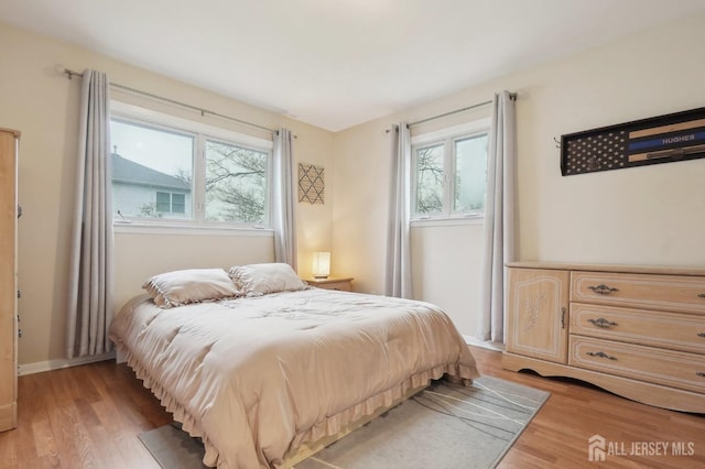 bedroom featuring baseboards, multiple windows, and light wood finished floors