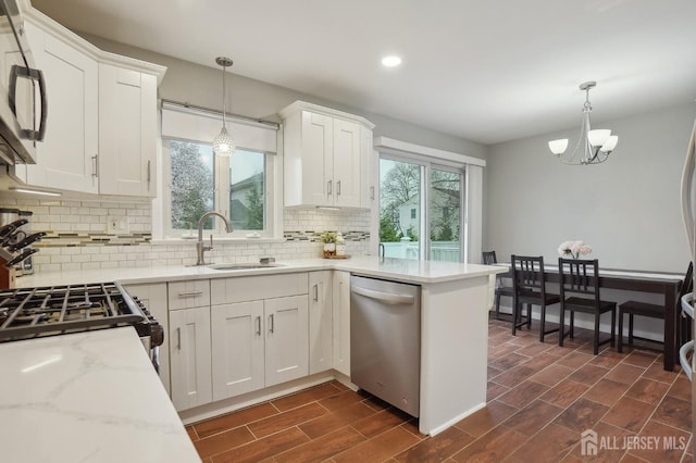 kitchen featuring white cabinets, a sink, appliances with stainless steel finishes, recessed lighting, and backsplash