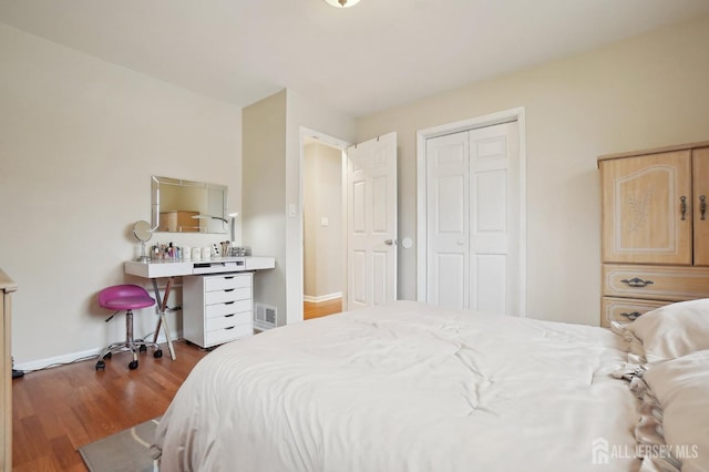 bedroom with visible vents, baseboards, a closet, and wood finished floors