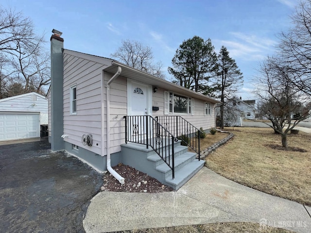 520 Hayward St, Bound Brook, NJ 08805 - view of front of property with a chimney, asphalt driveway, an outbuilding, and a garage