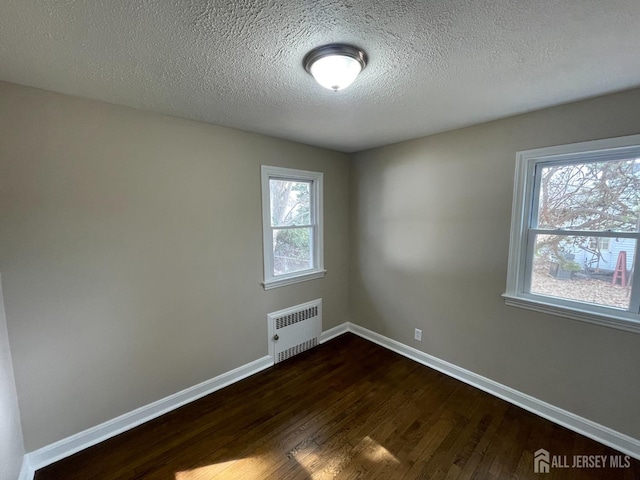 520 Hayward St, Bound Brook, NJ 08805 - spare room with radiator heating unit, dark wood-style floors, baseboards, and a textured ceiling