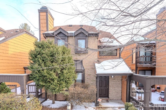 view of front of property featuring a chimney and brick siding