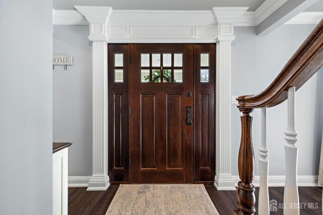 foyer entrance with dark wood-type flooring, ornamental molding, and decorative columns