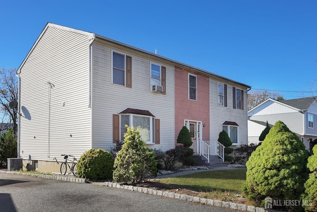 view of front of home with cooling unit and a front lawn