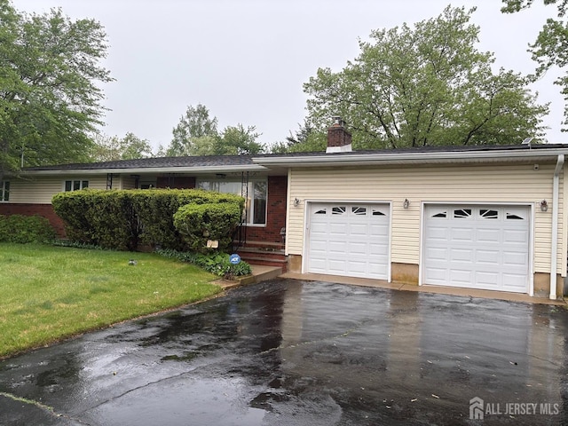 ranch-style home featuring asphalt driveway, a chimney, an attached garage, and a front lawn