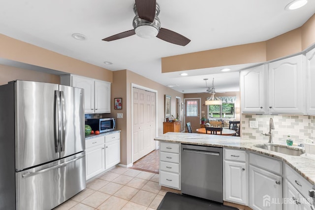 13 Quincy Rd, East Brunswick, NJ 08816 - kitchen featuring appliances with stainless steel finishes, white cabinetry, decorative backsplash, light stone countertops, and a peninsula