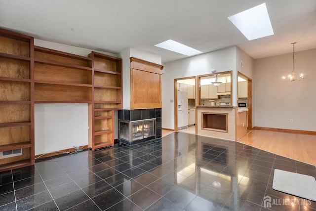 352 Lancaster Ct, Piscataway, NJ 08854 - unfurnished living room with a tiled fireplace, a skylight, baseboards, and a chandelier
