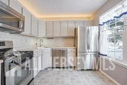 kitchen with a sink, decorative backsplash, stainless steel appliances, and light countertops