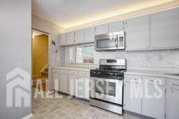 kitchen with appliances with stainless steel finishes, light countertops, and gray cabinetry