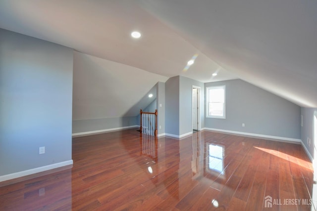 bonus room with dark hardwood / wood-style flooring and vaulted ceiling