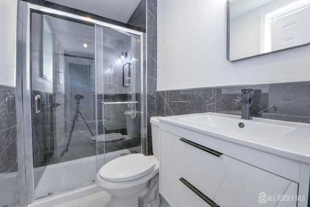 bathroom featuring an enclosed shower, vanity, toilet, and tile walls