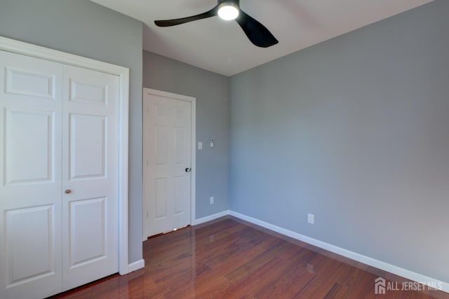 unfurnished bedroom with dark hardwood / wood-style flooring, a closet, and ceiling fan