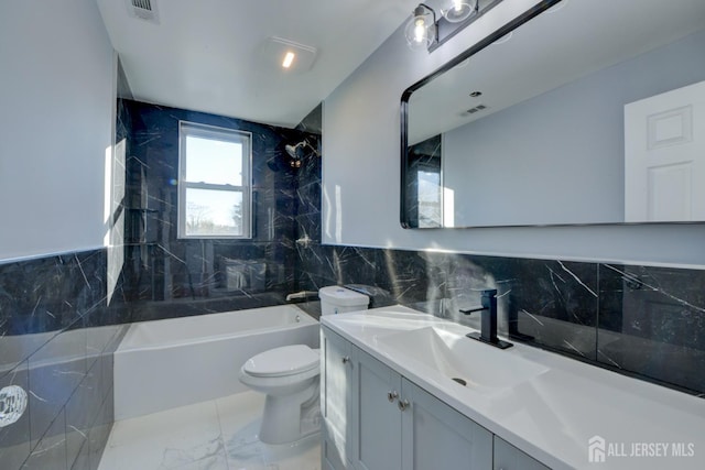 full bathroom featuring tile walls, vanity, tiled shower / bath combo, and toilet