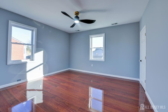 unfurnished room featuring ceiling fan, a healthy amount of sunlight, and dark hardwood / wood-style flooring