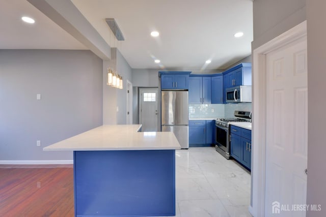 kitchen featuring light wood-type flooring, backsplash, stainless steel appliances, blue cabinetry, and a center island