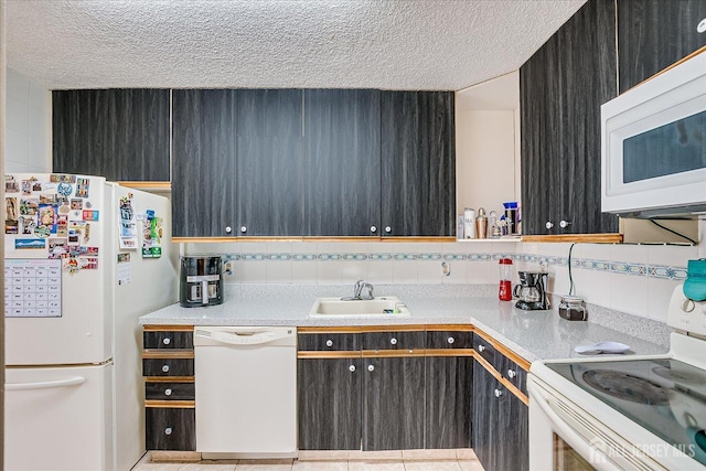 kitchen featuring decorative backsplash, white appliances, a sink, and a textured ceiling