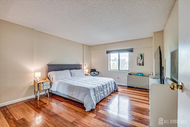bedroom featuring wood-type flooring, a textured ceiling, and baseboards