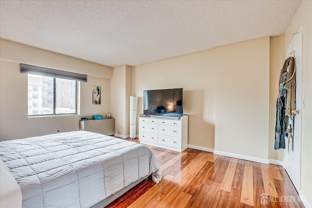 bedroom featuring baseboards, a textured ceiling, and light wood-type flooring