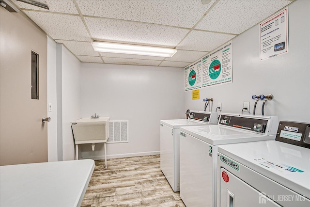 common laundry area with baseboards, washer and clothes dryer, visible vents, and light wood-style flooring