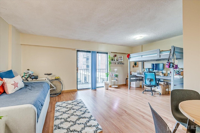 bedroom with baseboards, wood finished floors, access to outside, and a textured ceiling