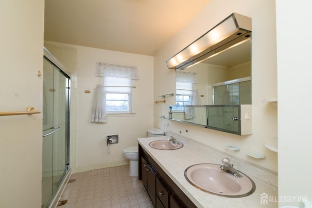 full bath featuring double vanity, a sink, a stall shower, and toilet