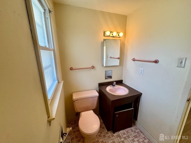 half bathroom featuring vanity, baseboards, and toilet
