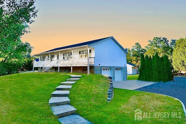 view of front of home with a porch, a yard, and a garage