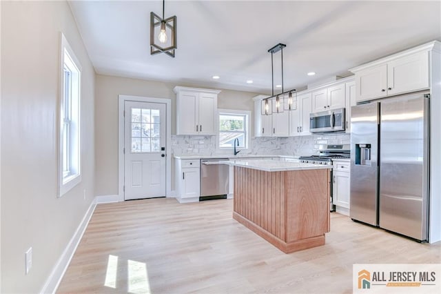 32 Campbell Ave, Edison, NJ 08817 - kitchen featuring appliances with stainless steel finishes, decorative backsplash, a center island, light wood-style floors, and light countertops