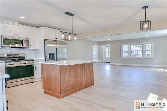 32 Campbell Ave, Edison, NJ 08817 - kitchen featuring appliances with stainless steel finishes, light wood-style floors, a kitchen island, white cabinetry, and plenty of natural light