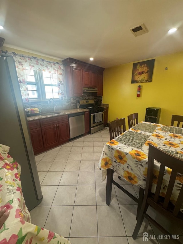 kitchen featuring tasteful backsplash, visible vents, light tile patterned flooring, stainless steel appliances, and a sink