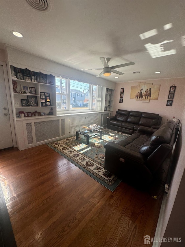 living room featuring ceiling fan, visible vents, built in features, and wood finished floors